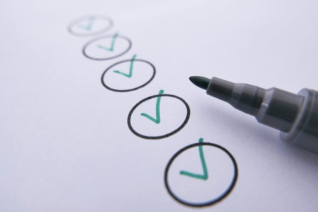 Close-up of a checklist with green checkmarks on white paper using a marker.